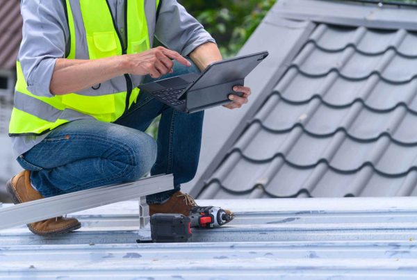 Roofing contractor performing a fall inspection on a metal roof.